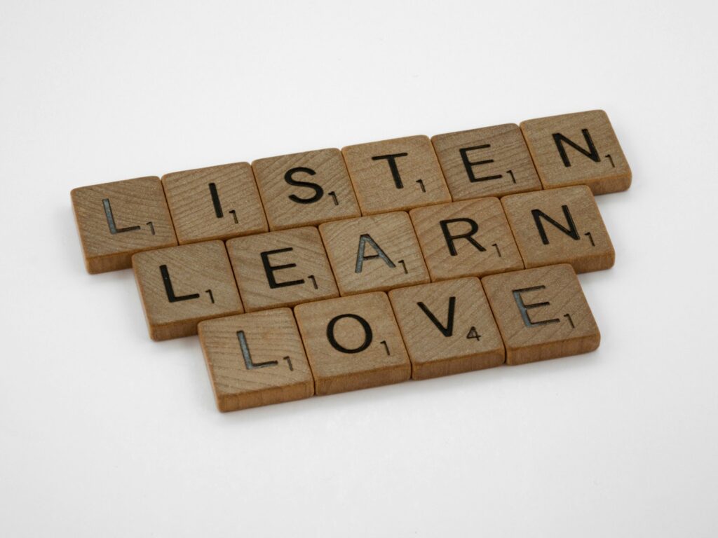 brown wooden blocks on white surface: listen, learn, love (Zuhören, Lernen, Lieben)